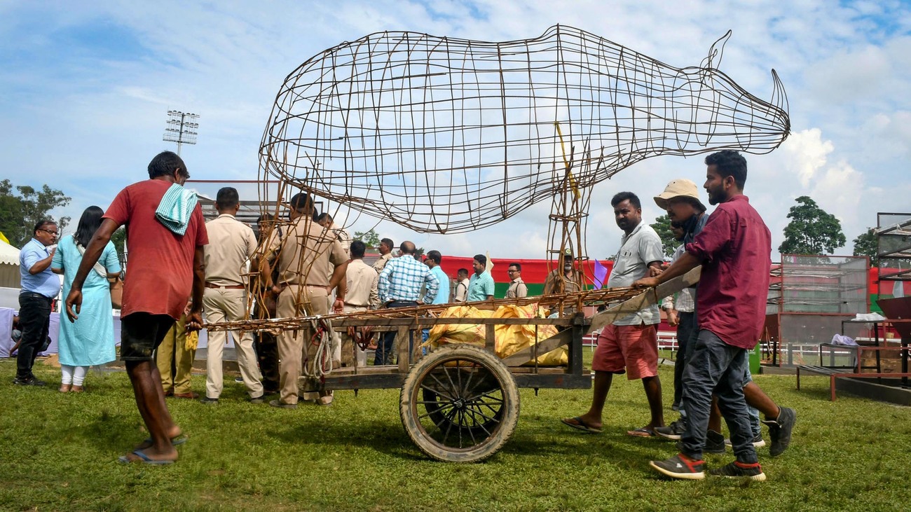 men wheel an iron cast image of a rhino for World Rhino Day