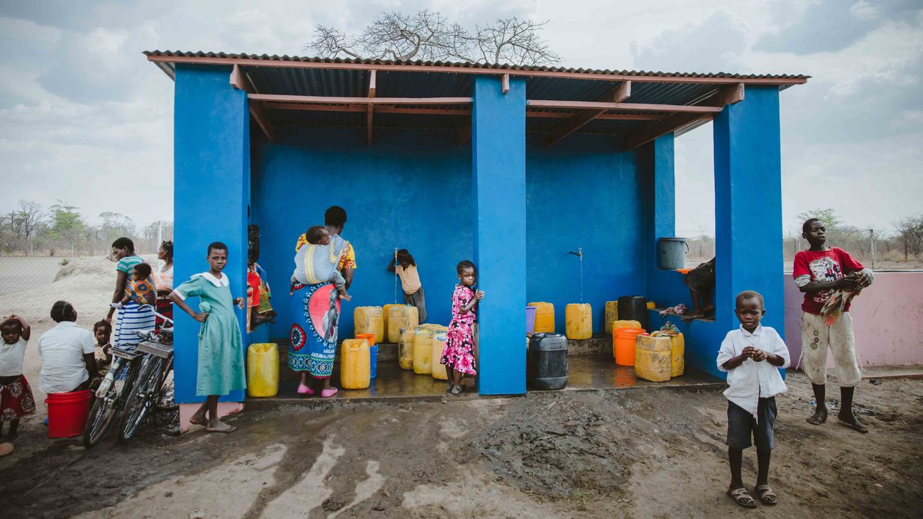 women and children gather around water station