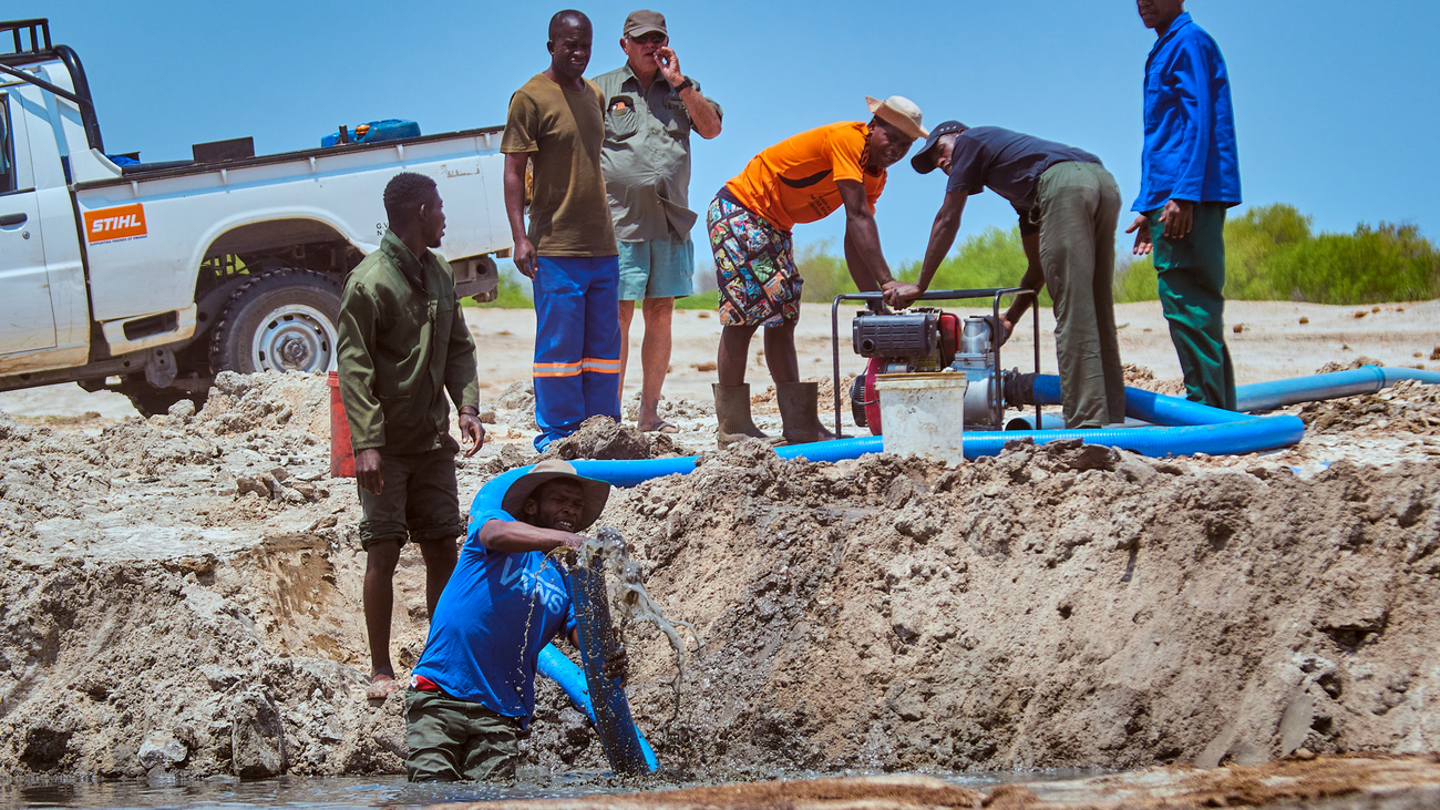 Men adding water to basin in Zimbabwe