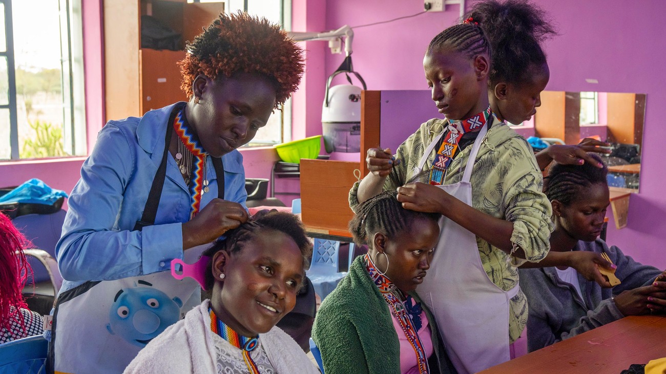 Drie deelnemers aan Jenga Mama oefenen met kapperswerk in een kapsalon.