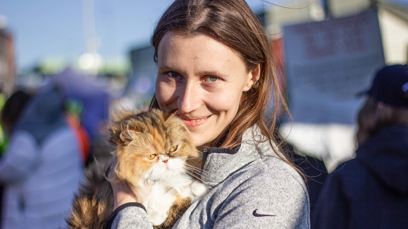 a woman smiles while holding a cat