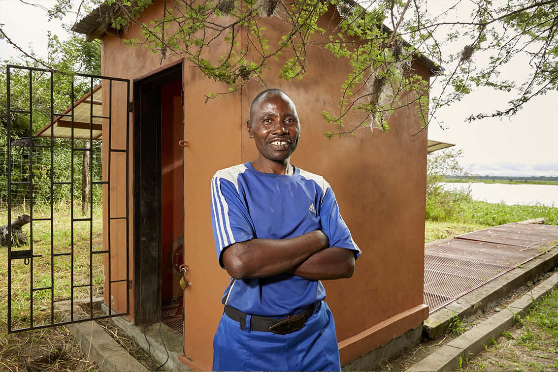 Dias in front of the structure that houses the Chikolongo Livelihood Project solar water pump, Liwonde National Park, Malawi.