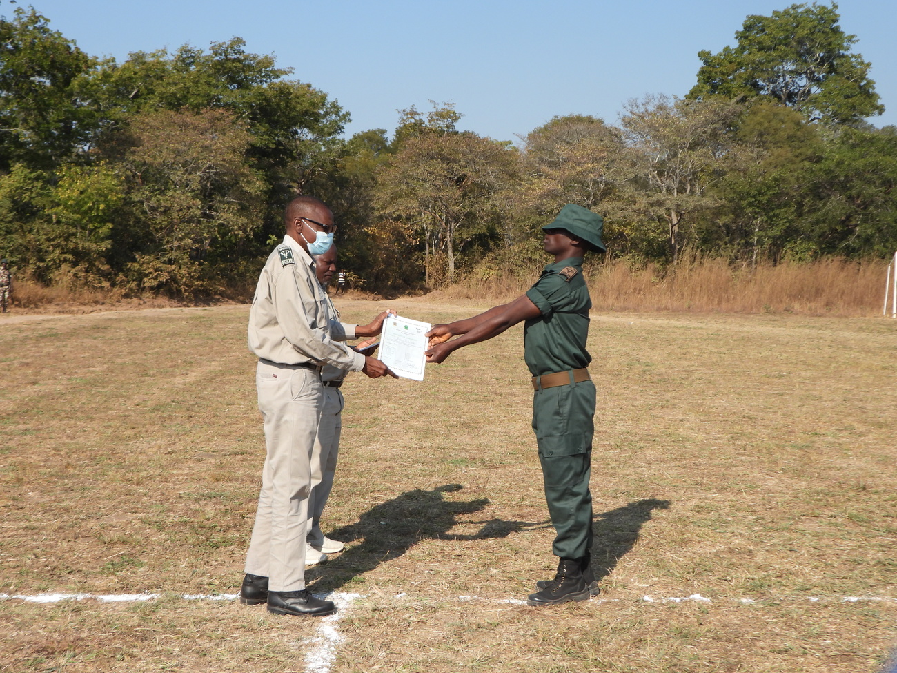 Brighton Kumchedwa, Director of the Malawi Department of National Parks and Wildlife, presents a graduation certificate to a fence attendant at Kasungu National Park, Malawi