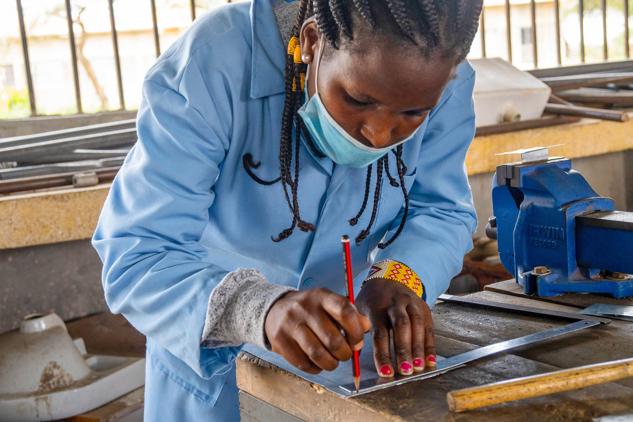 Jenga Mama participant and plumbing student Janet Sabore uses a ruler to mark a piece of metal during vocational training.