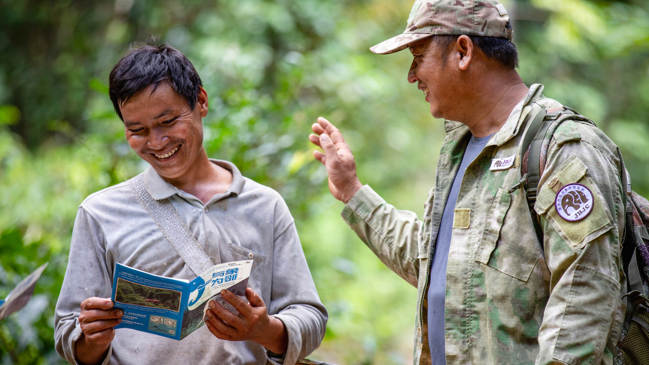 A community ranger promotes safety precautions for Asian elephant encounters to a villager going into the mountains to pick mushrooms.