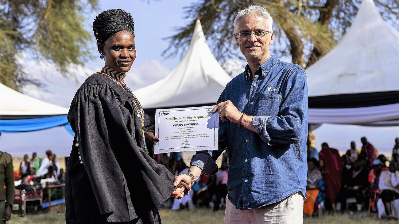 IFAW-Länderdirektor Deutschland Robert Kless und eine Frau aus dem IFAW-Projekt Jenga Mama schütteln sich die Hände und halten eine Urkunde in der Hand.