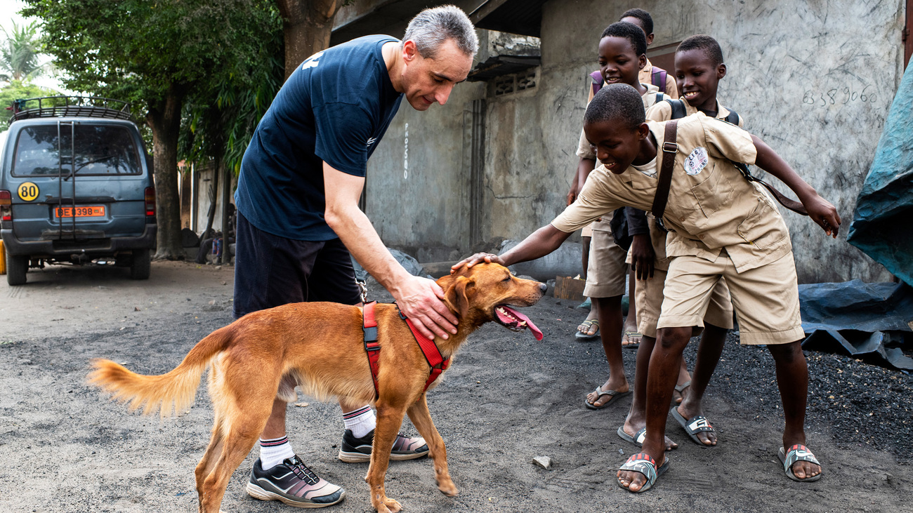 Volunteer veterinarian Dr. Thierry Lamour encourages children from the local community in Benin to interact with detection dogs in a safe manner, to help people understand they do not need to be afraid of them.