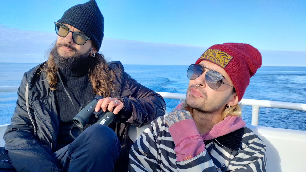 Tom und Bill Kaulitz auf einem Boot. Sie blicken interessiert zu einer Person außerhalb des Bildes, die ihnen mehr über IFAWs Arbeit erzählt.