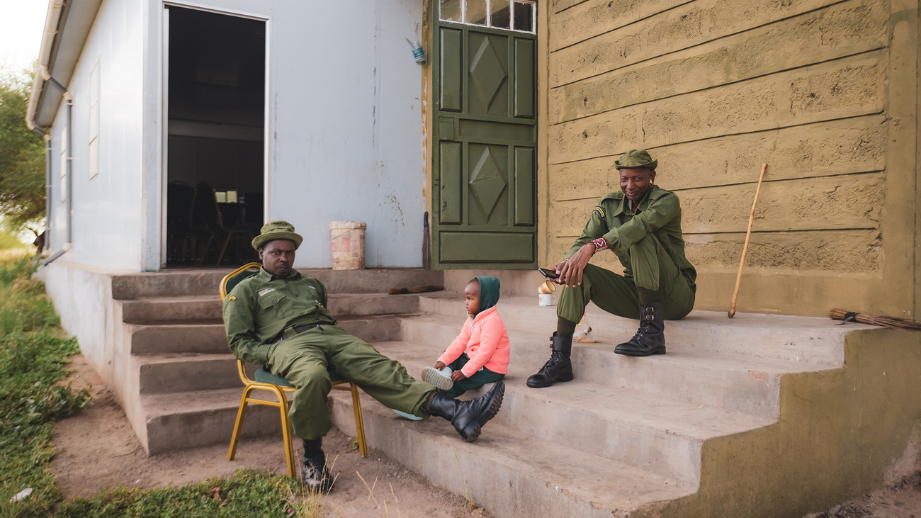 Two male rangers stay behind to care for a teammate’s child while Team Lioness heads out on patrol—an unexpected and welcome moment of role reversal at the Amboseli ranger base.