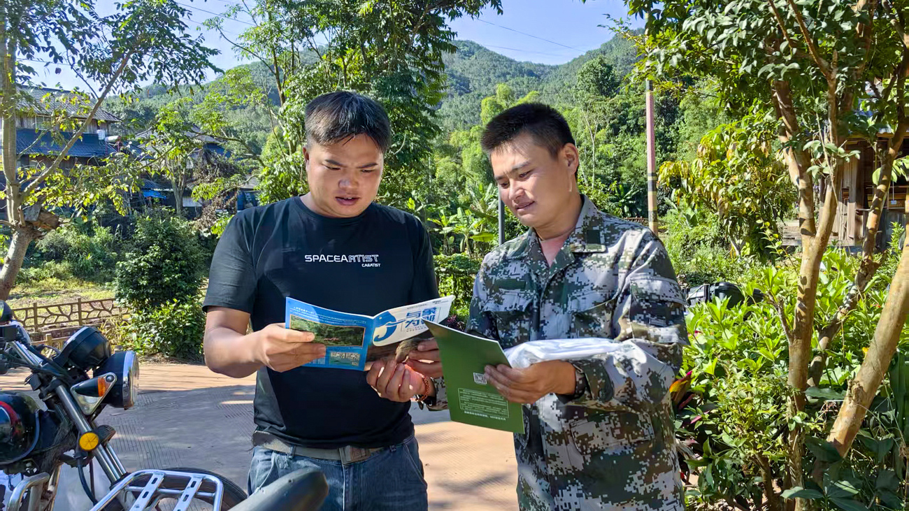 rangers Li Shengqian and Li Jie visit the village to educate residents heading to work on safety precautions and reinforce key messages to help prevent human–elephant conflict.