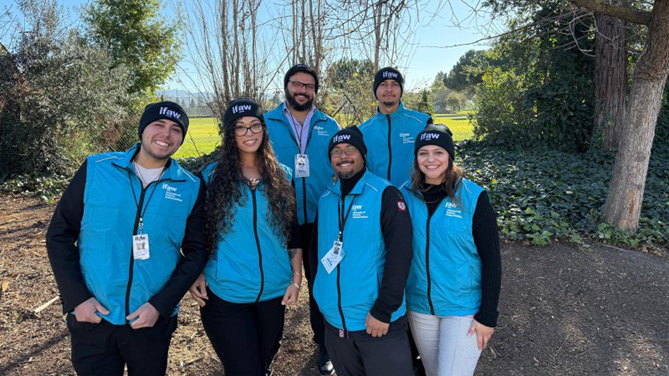 Sieben Personen stehen in blauer IFAW-Kleidung nebeneinander und lächeln freundlich in die Kamera.