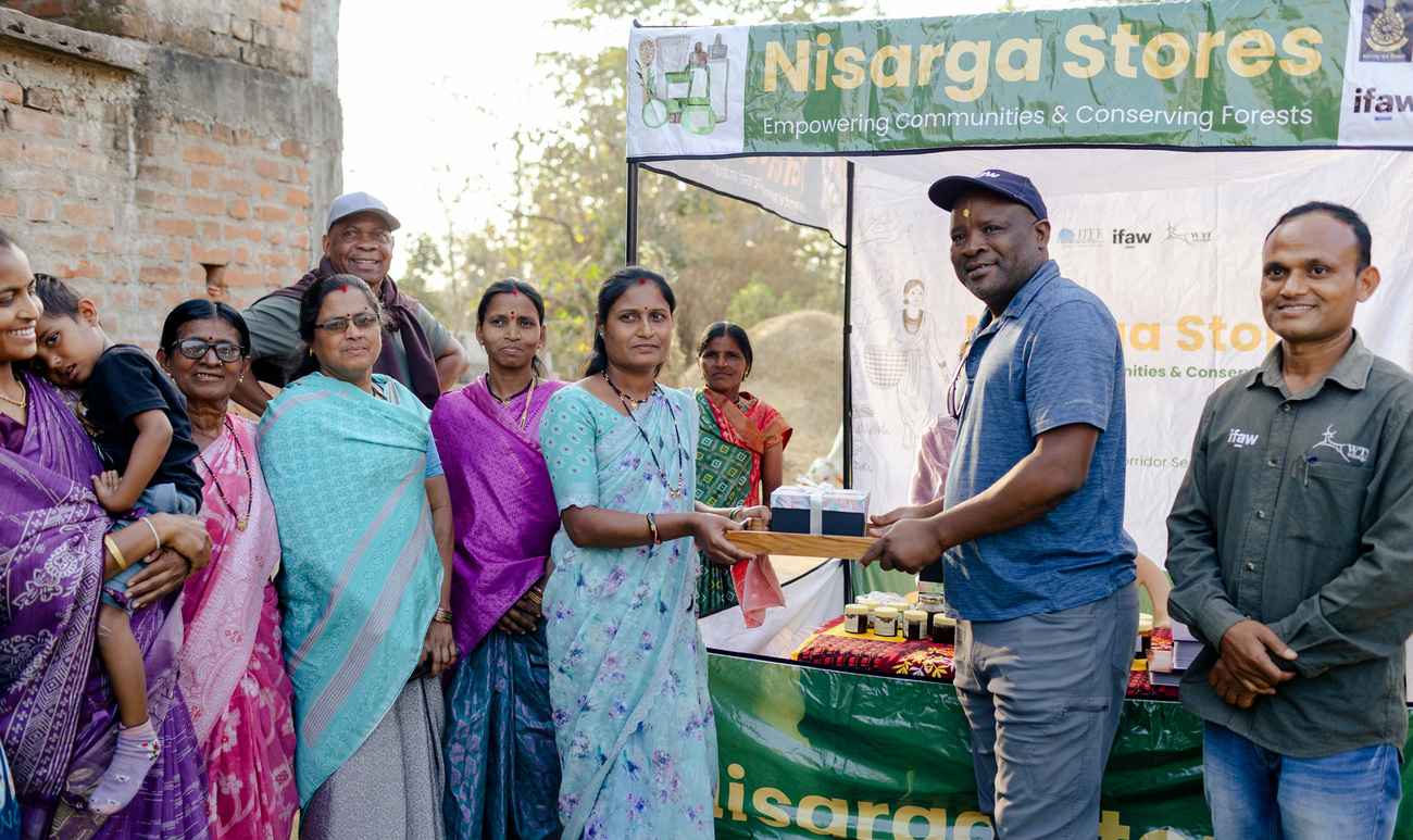 Women from a local livelihood enterprise present IFAW’s Enos Omandi with a selection of honey, turmeric, and other products they sell