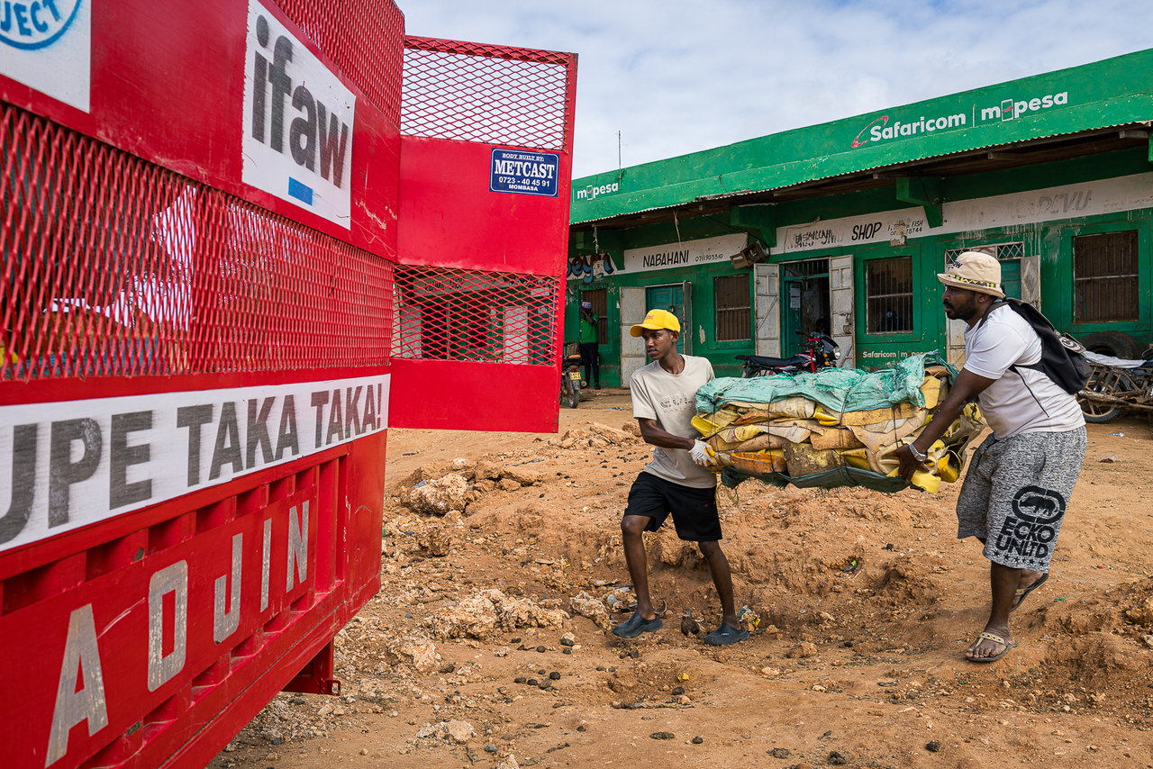 Workers carry a basket of collected waste on Pate Island, Kenya.